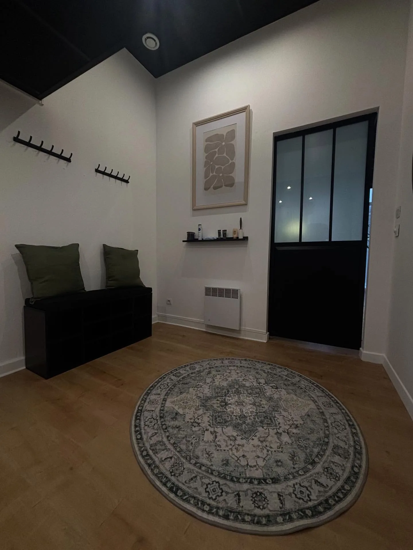 Le vestiaire du studio, banc noir, coussins vert sauge et verrière